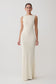 Woman wearing a long, off-white dress against a plain background