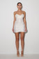 Woman wearing a strapless white sequin dress on a plain background
