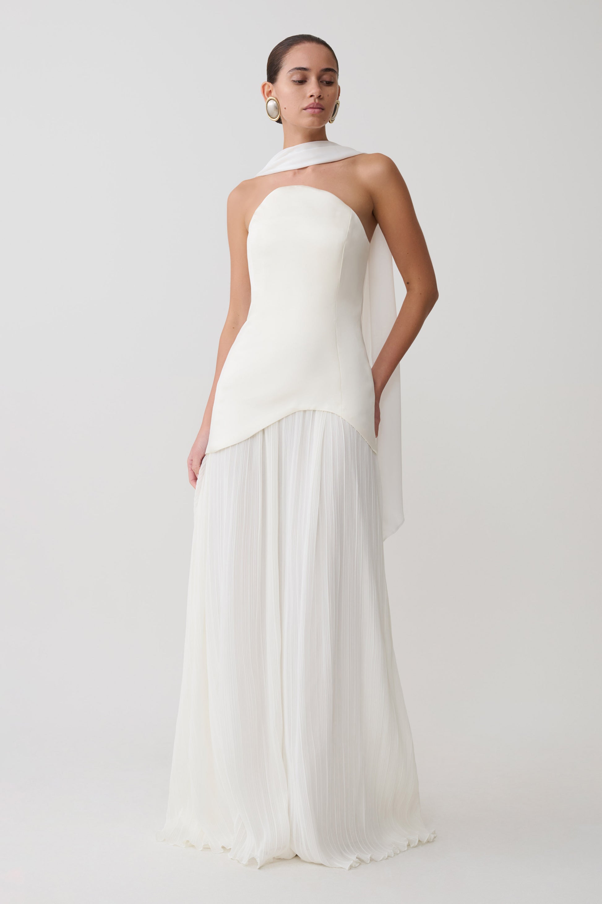 Woman wearing a white halter neck dress on a plain background