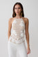 Woman wearing a white crochet halter top.