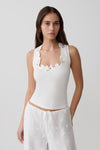 Woman wearing a white sleeveless broderie top.