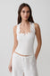 Woman wearing a white sleeveless broderie top.