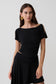 Woman wearing a black short sleeve off-shoulder top.