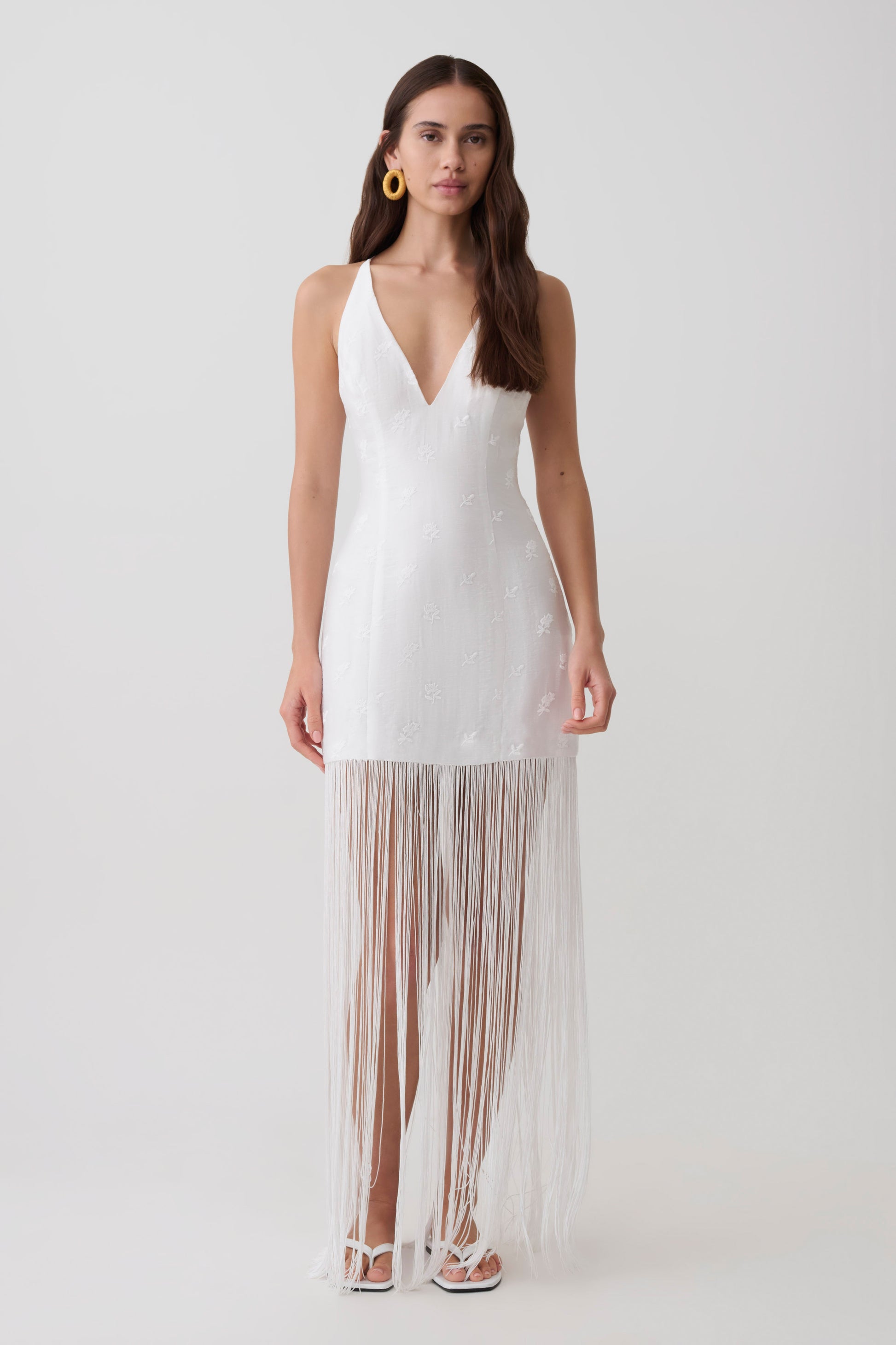 Woman wearing a v neck white fringe maxi dress.