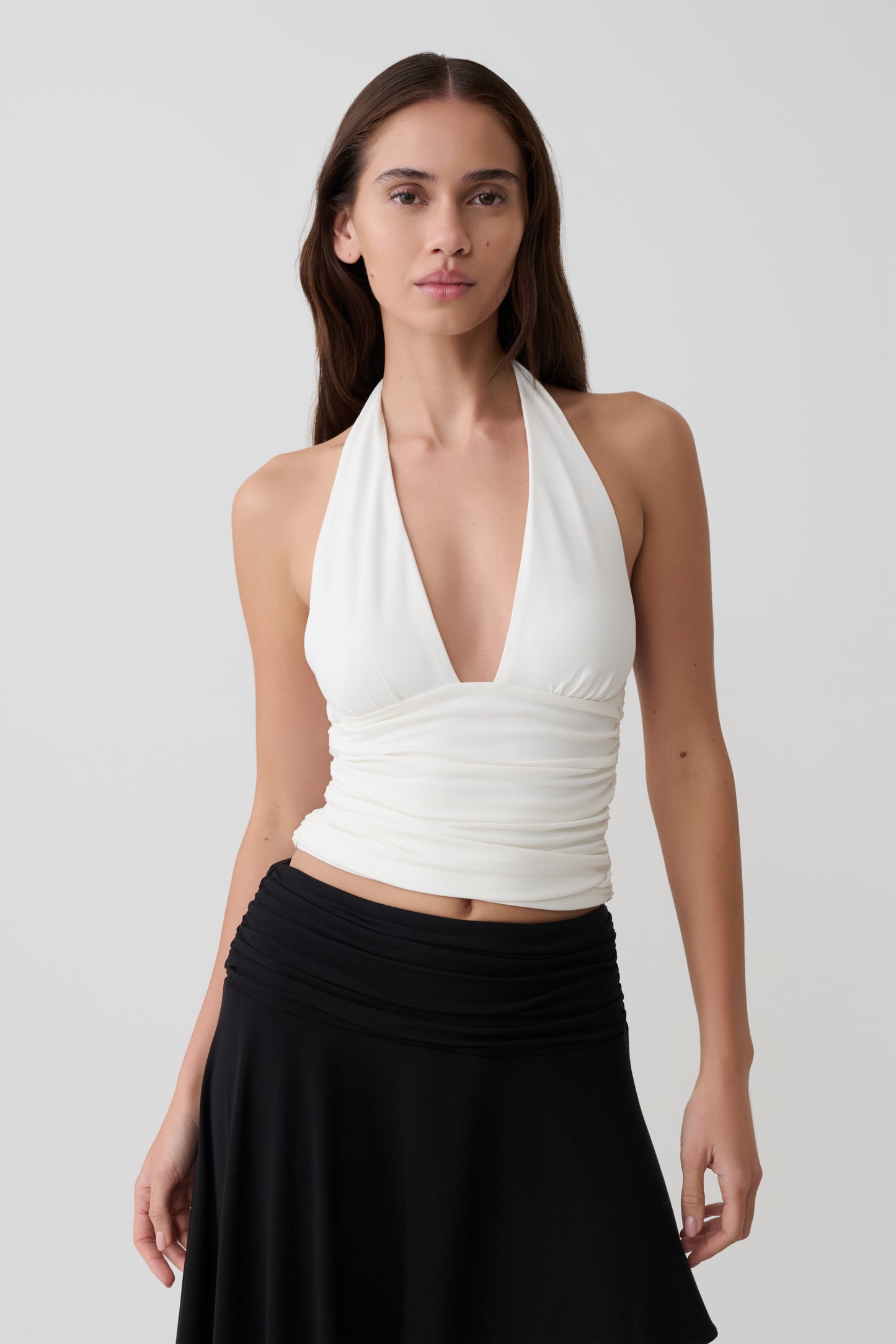 Woman wearing a white modal gathered halter top. 