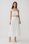 Woman wearing a white lace sleeveless crop top with matching panelled midi skirt.