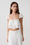 Woman wearing a whie lace sleeveless crop top.