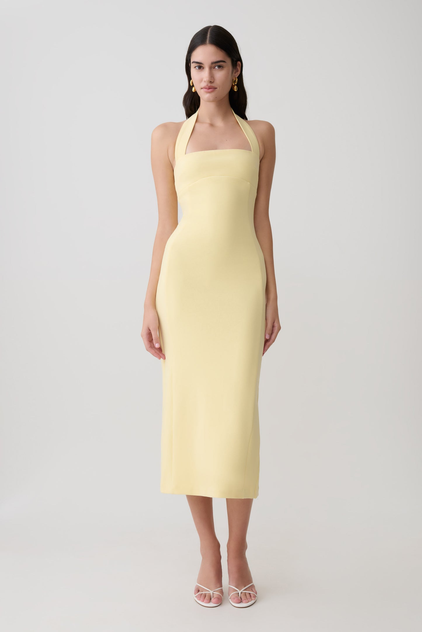Woman wearing a yellow suiting halter midi dress.
