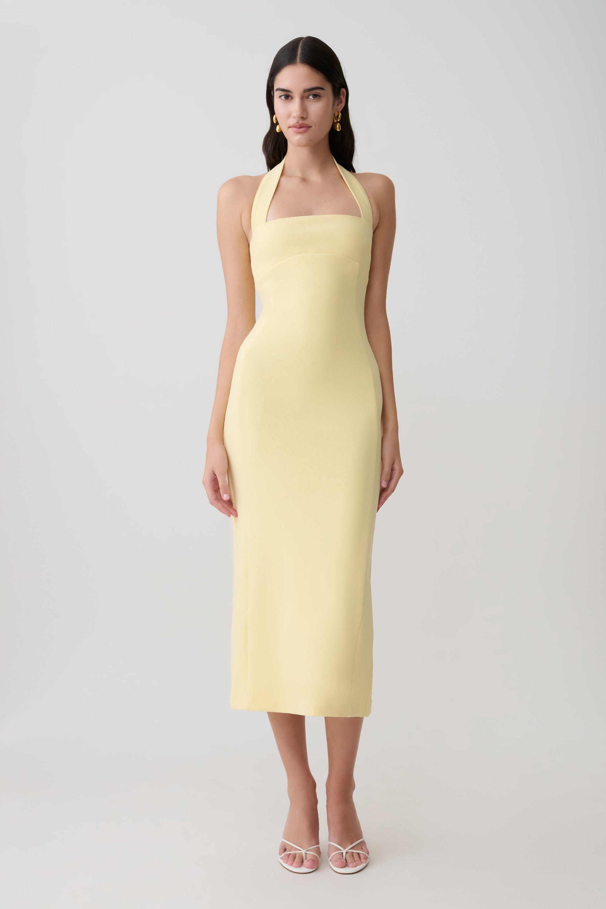 Woman wearing a yellow suiting halter midi dress.