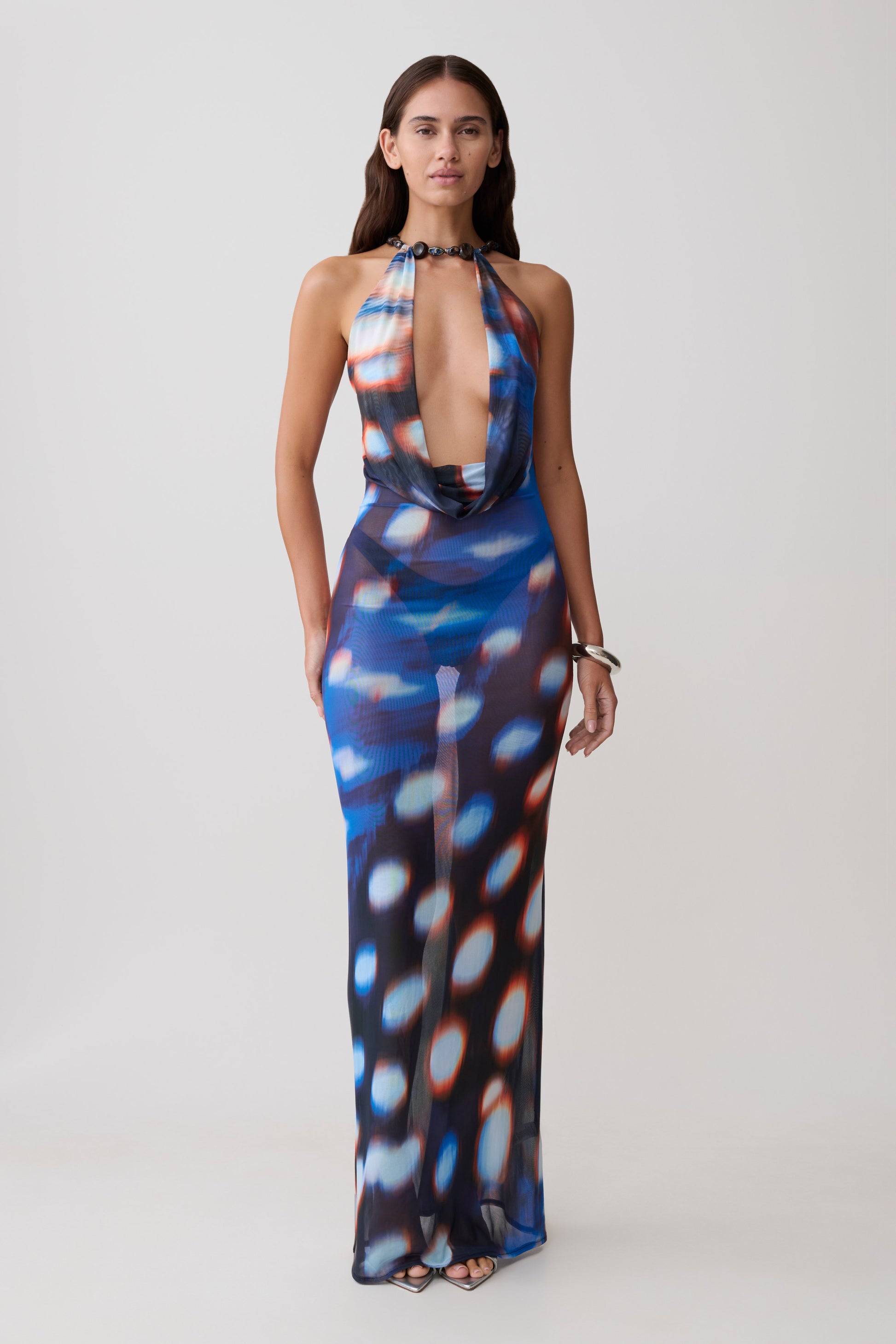 Woman wearing a colourful blue abstract print mesh cowl plunge maxi dress.