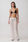 Woman wearing a black bikini top and sheer white drawstring wide pants.