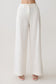 Woman wearing white straight leg linen pants.