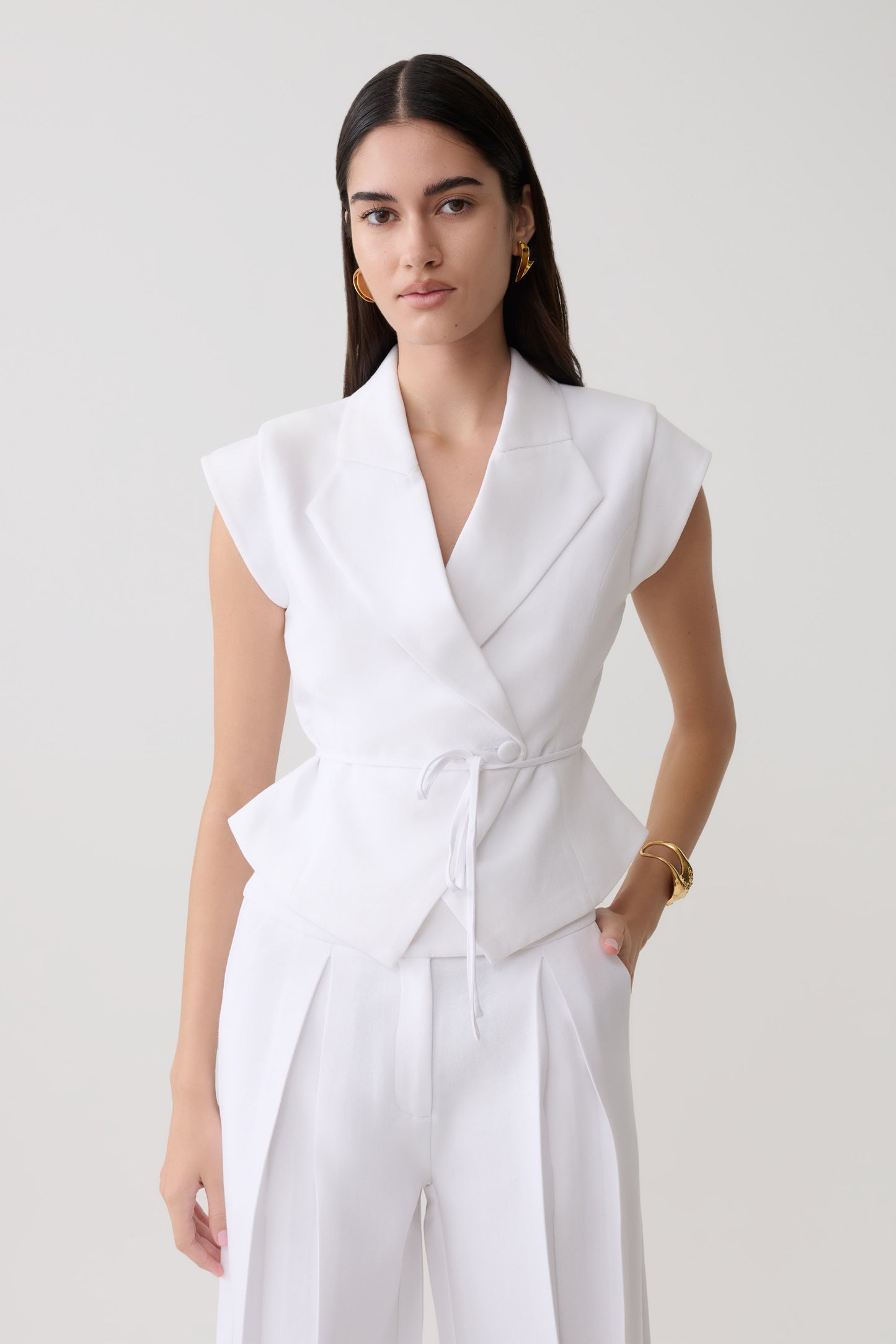 Woman wearing a white short sleeve linen top.