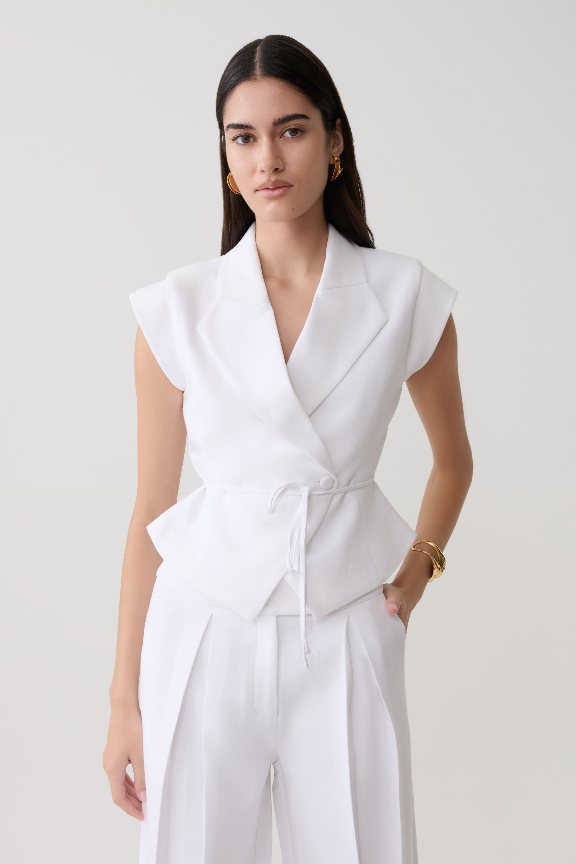 Woman wearing a white short sleeve linen top.