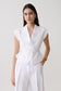 Woman wearing a white short sleeve linen top.