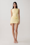 Woman wearing yellow draped mini dress.