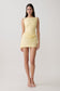 Woman wearing yellow draped mini dress.
