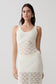 Woman wearing a white sleeveless crochet top.