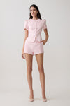 Woman wearing short sleeve pink satin top with matching shorts.