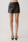 Woman wearing dark brown faux leather high waisted shorts.