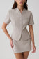 Woman wearing a grey suiting short sleeve top.