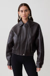 Woman wearing a brown faux leather cropped jacket.