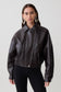 Woman wearing a brown faux leather cropped jacket.