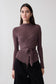 Woman wearing a mauve wrap knit long sleeve top with a tie detail.