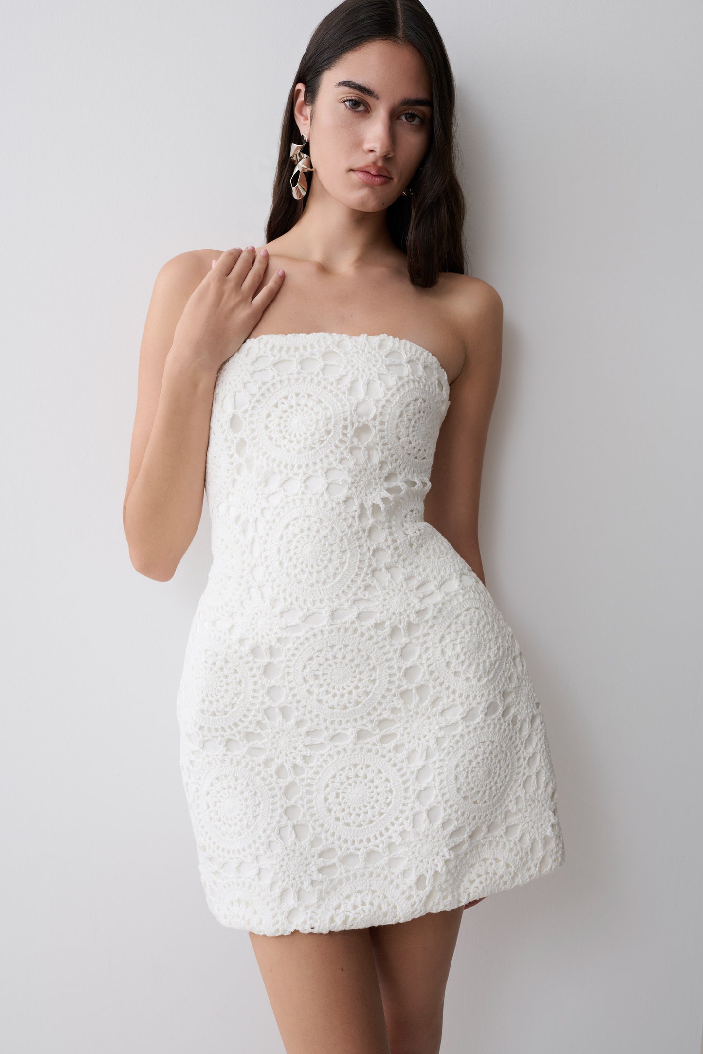 Woman wearing a white strapless crochet mini dress.