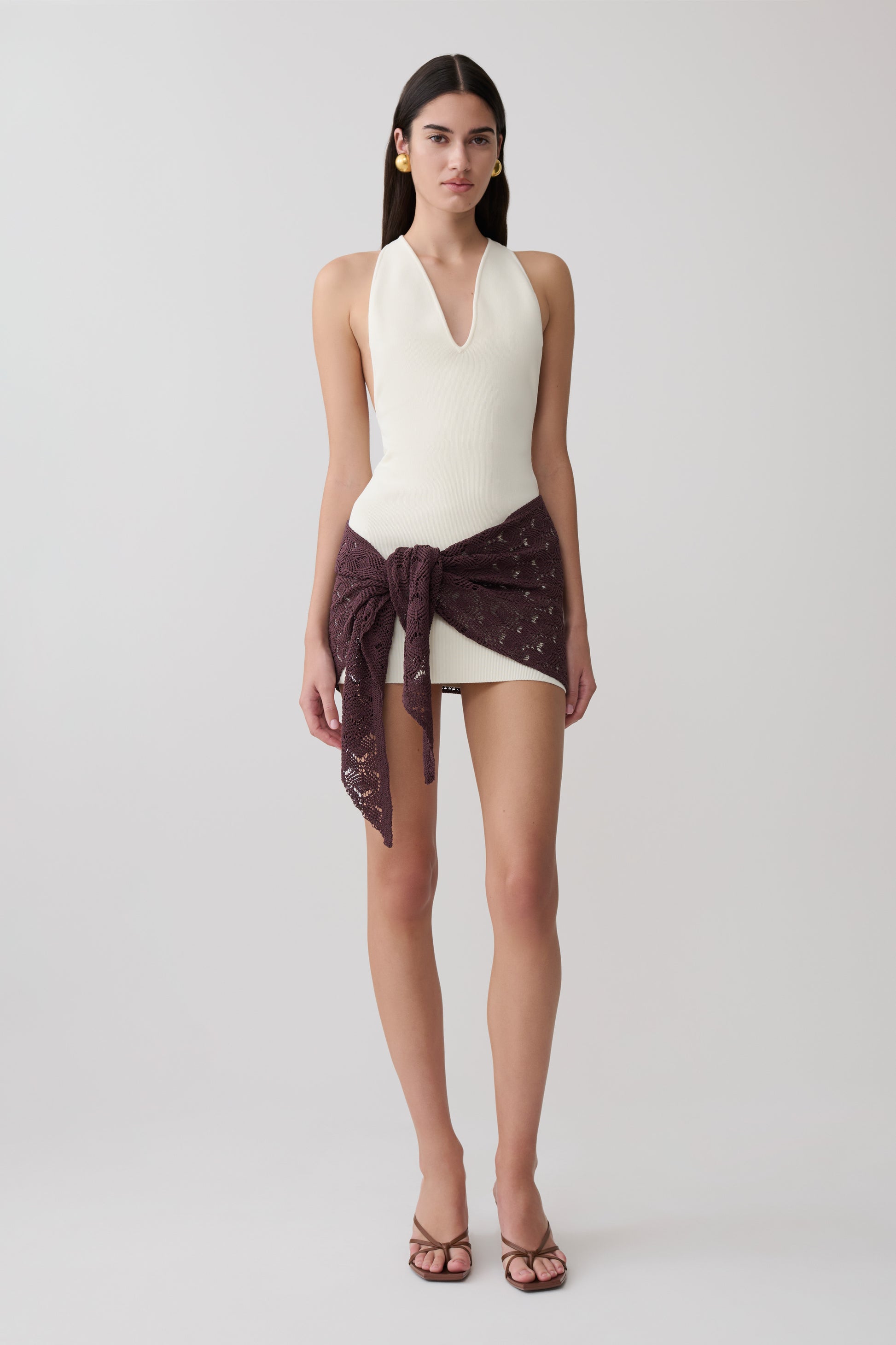 Woman wearing a white mini Dress with a brown crochet overlay.