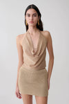 Woman wearing a gold lurex cowl neck top.