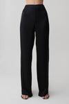 Woman wearing black straight leg satin pants.