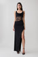 Woman wearing a black draped slinky and lace maxi dress.