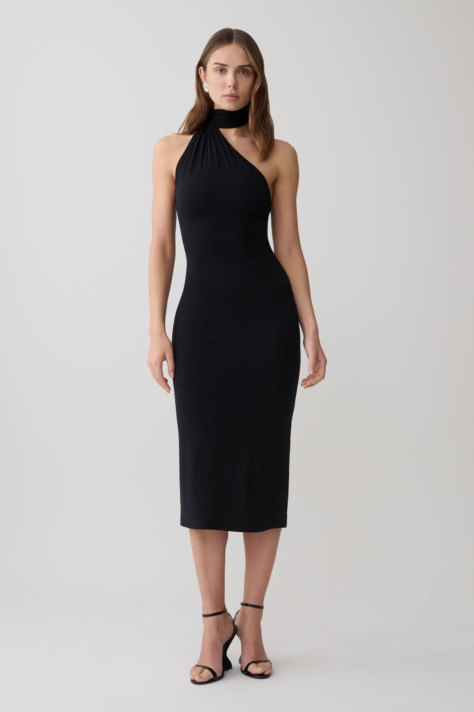 Woman wearing a black one shoulder tie midi dress.