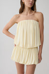 Woman wearing a light yellow strapless gathered bubble mini dress.