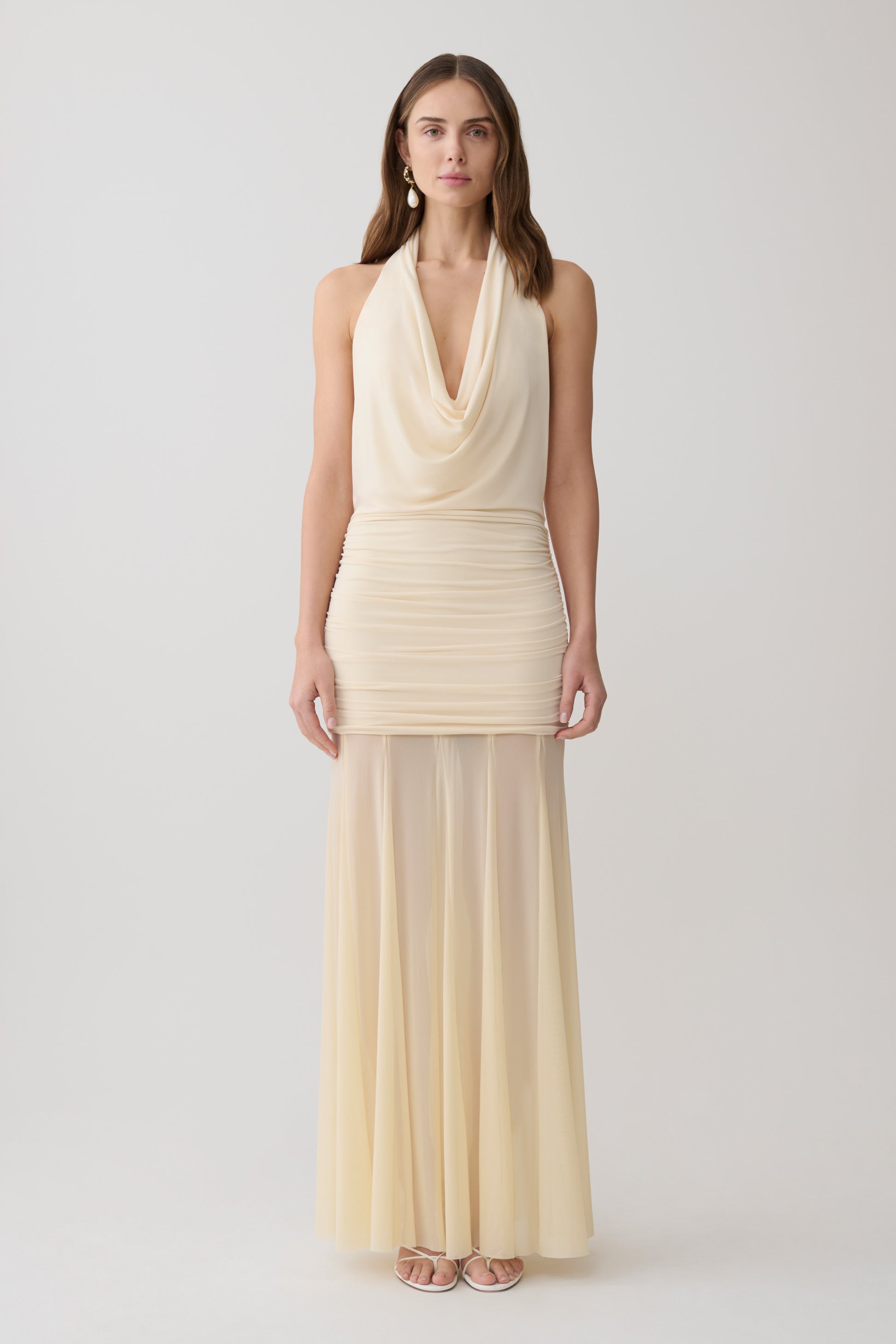 Woman wearing a white draped halter slinky maxi dress.
