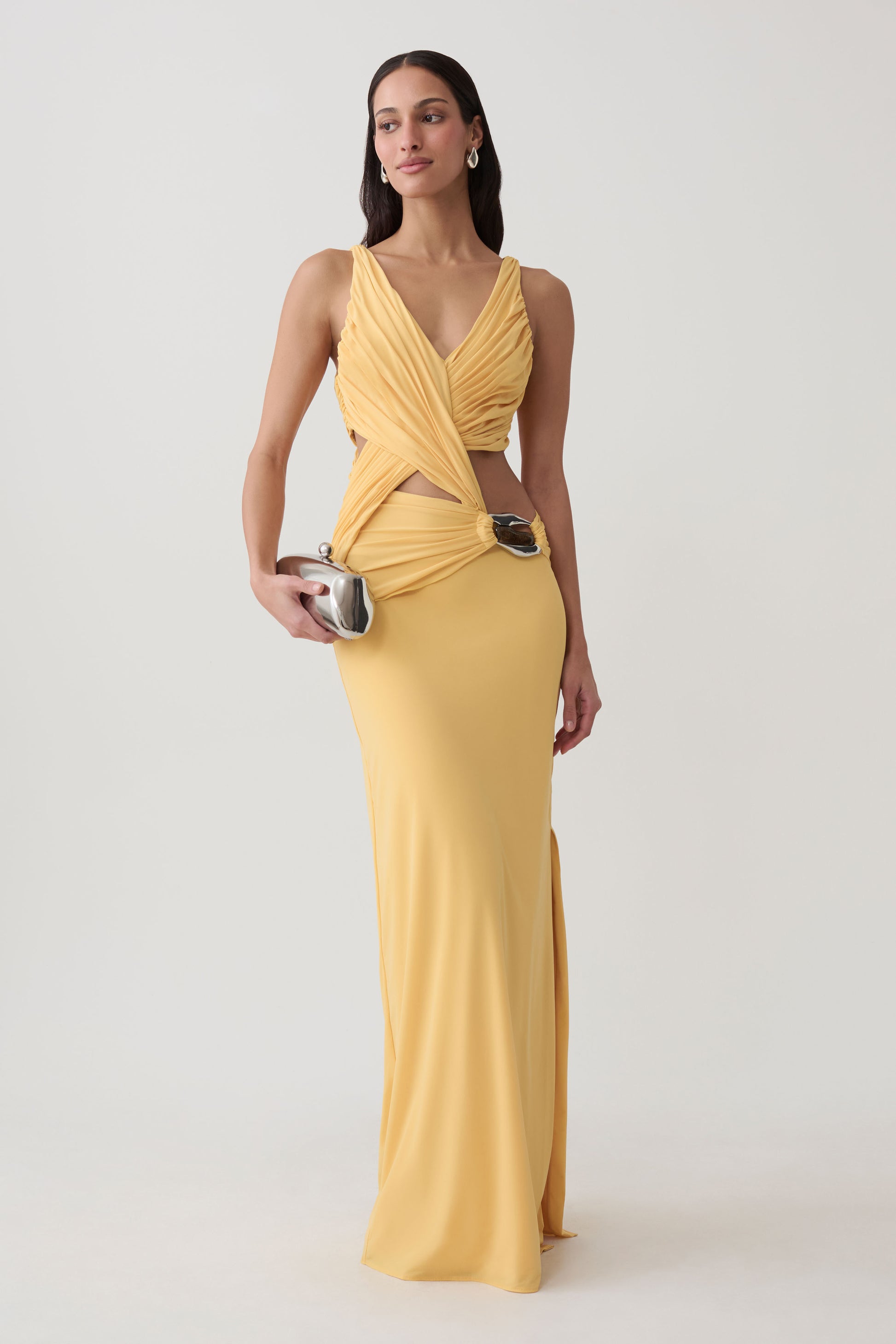 Woman wearing yellow draped jersey gown with hardware.