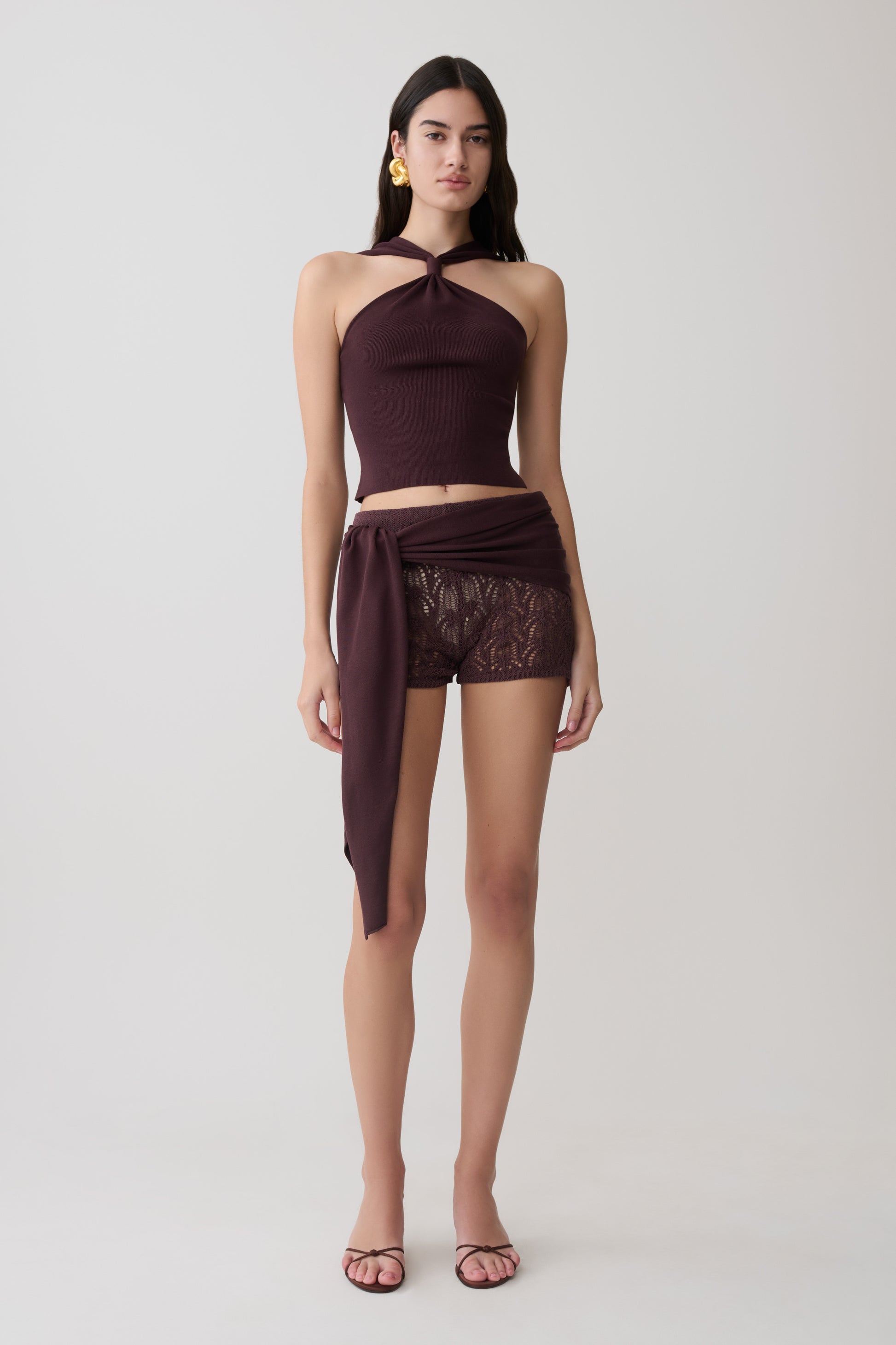 Woman wearing a brown twist front knit top with matching crochet shorts.