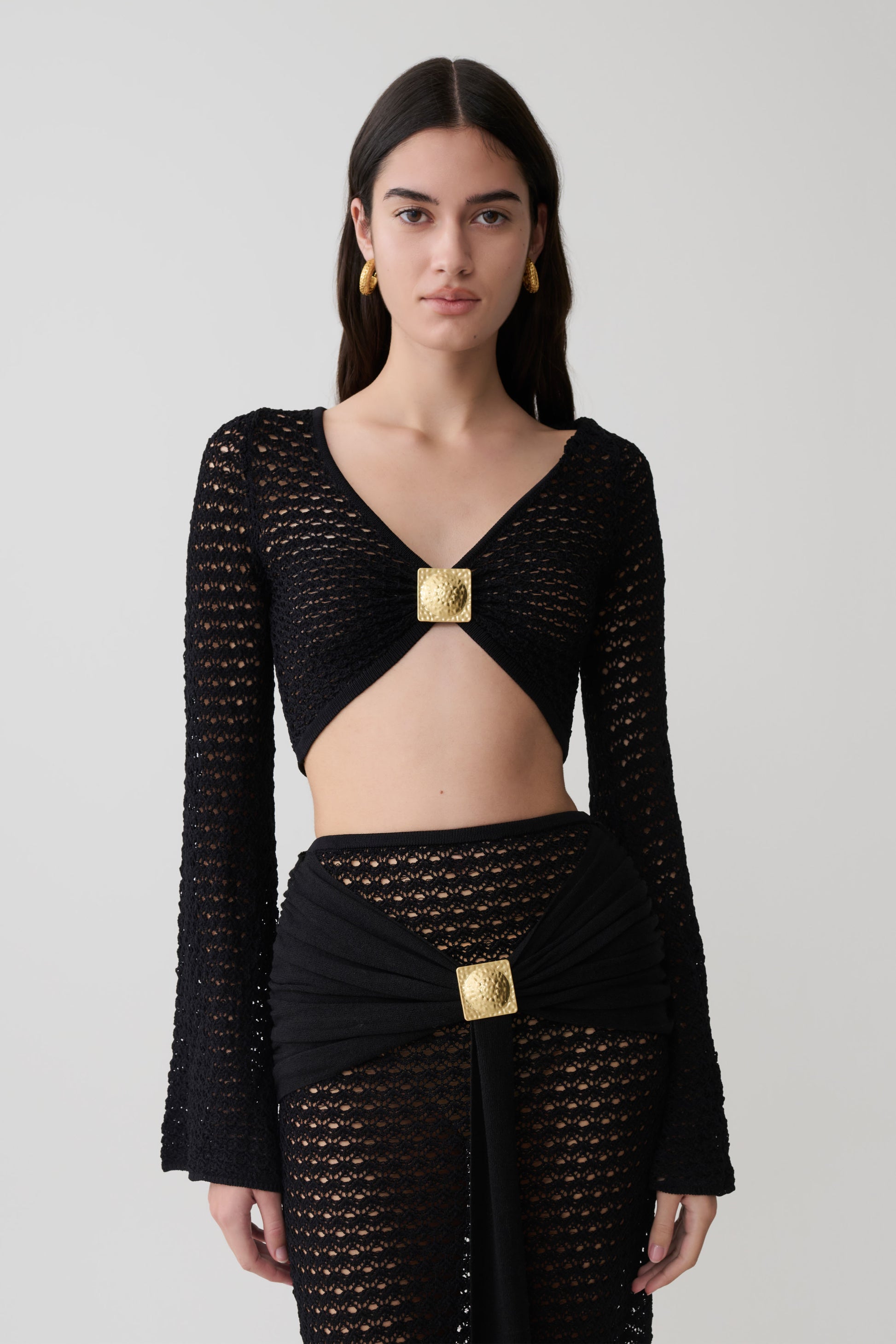 Woman wearing a black crochet long sleeve cropped top.
