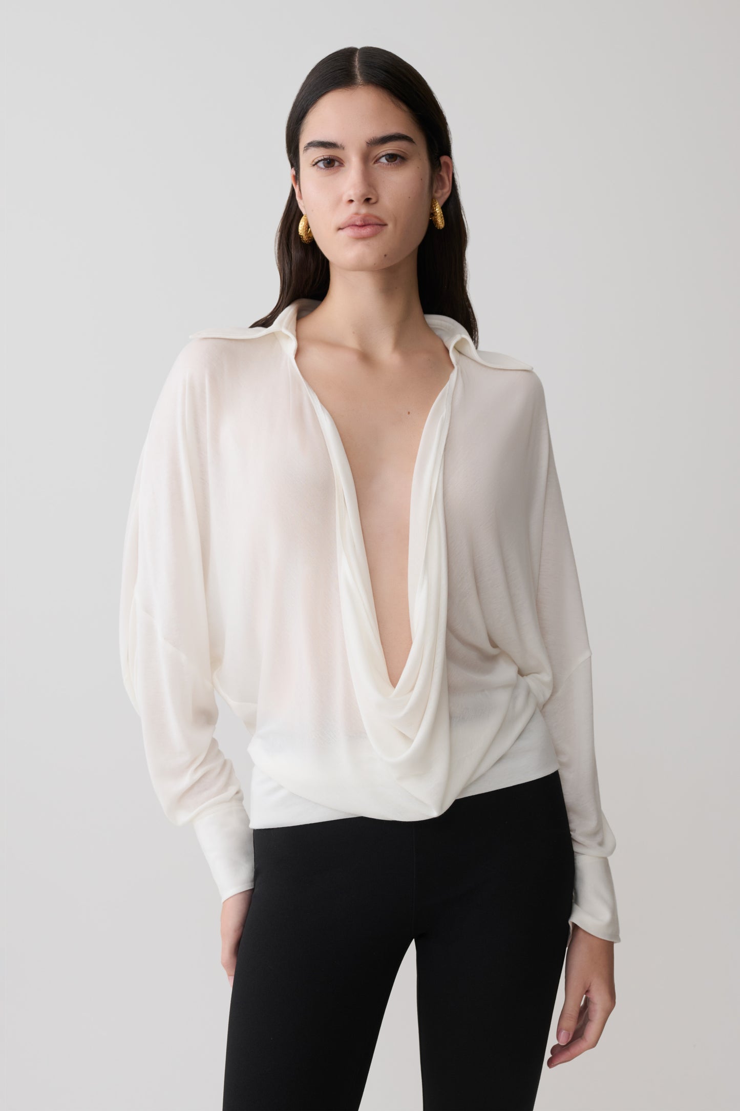Woman wearing a white blouse with a plunging neckline.