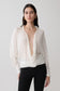 Woman wearing a white blouse with a plunging neckline.