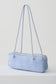 A light blue suede shoulder bag with a long, slender cylindrical body and matching shoulder straps, shown on a clean white studio background.