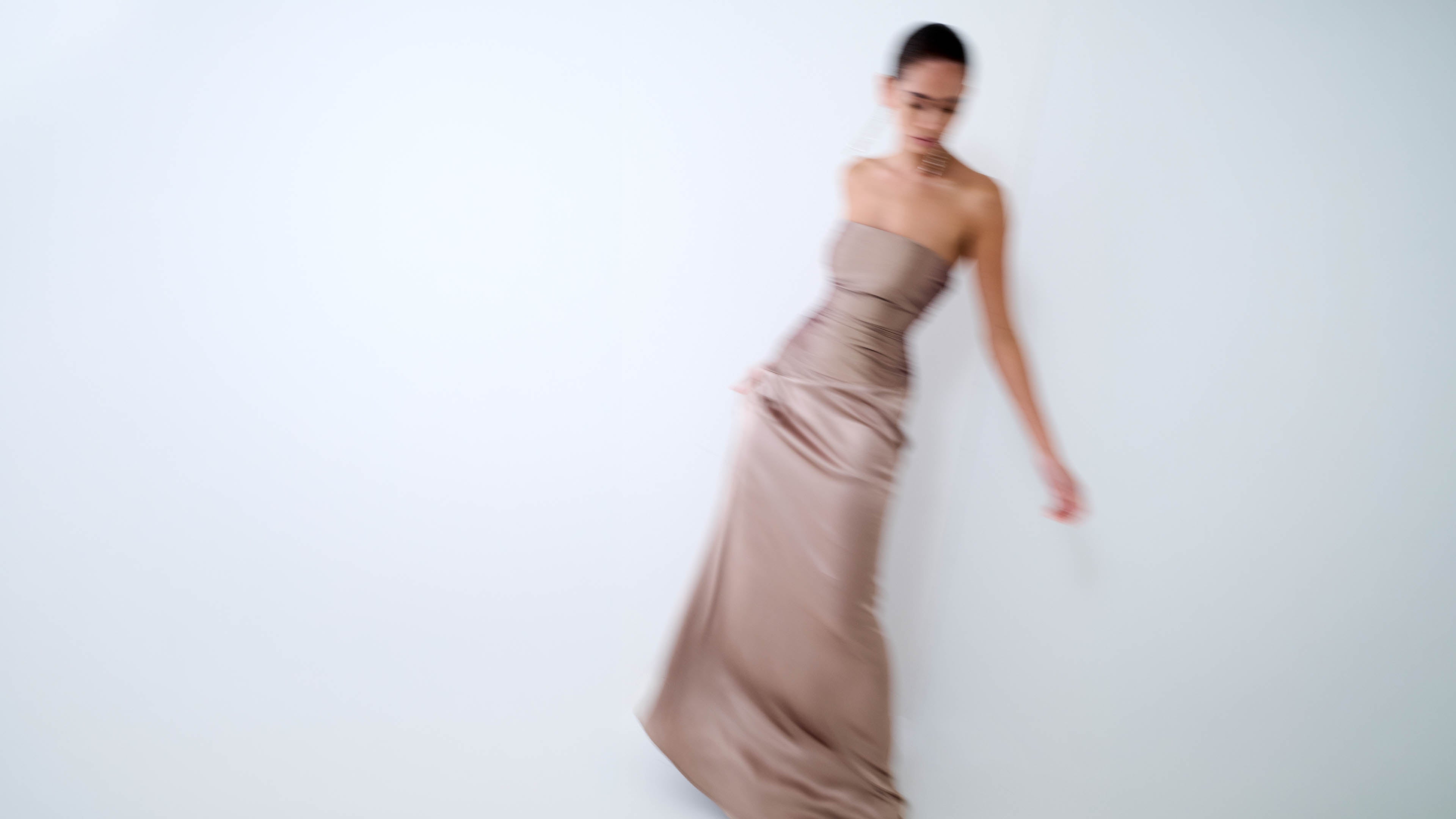 Woman wearing a strapless bronze taupe maxi dress.