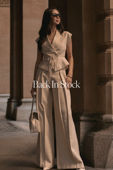 Woman in a beige suit standing in front of architectural columns with 'Back In Stock' text overlay.