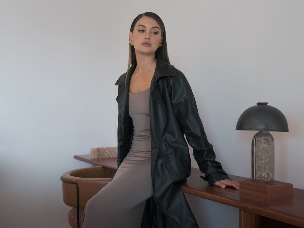 Image of woman in taupe dress with black trench coat.