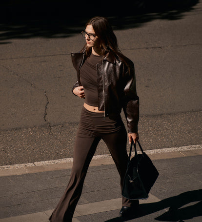 Image of woman in chocolate knit set and faux leather jacket.