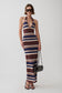 A woman modeling a sleeveless halter-neck maxi dress with horizontal stripes in navy blue, brown, beige, and white. She is wearing dark sunglasses and holding a small black handbag against a plain light gray studio background.