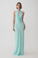 A woman modeling a sleeveless mint green maxi dress with a high mock neck, draped cowl neckline, sheer lace inserts at the bust and waist, and a flowing skirt, photographed against a light gray studio background.