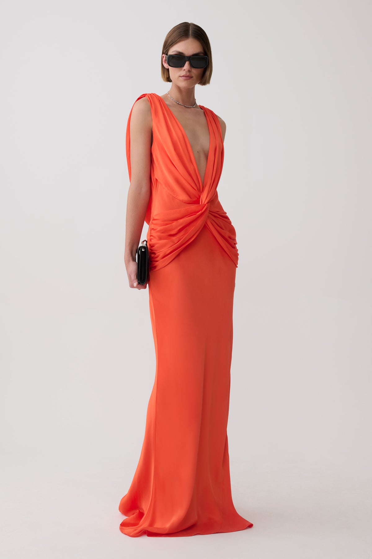 Woman wearing an orange v neck satin maxi dress.