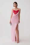 A model wearing a light pink slip-style maxi dress with a sweetheart neckline, sheer mesh bust, and a high thigh slit, paired with a bright red mesh corset mini dress underlayer and holding a small silver clutch against a plain light gray studio background.